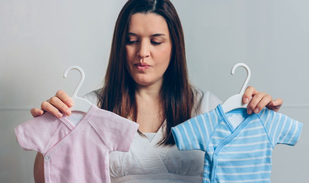 Pregnant woman choosing baby bodysuits