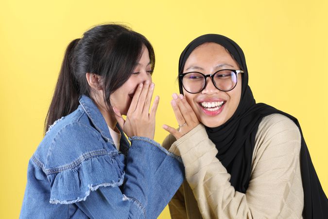 Two Young Asian Indonesian Women, Hand on Mouth Telling Gossip Secret Rumor