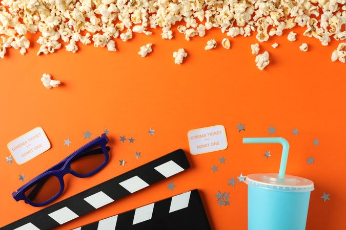 Flat lay. Popcorn, clapperboard, 3d glasses, drink and tickets on orange background, copy space