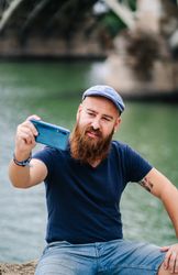 Satisfied male tourist taking selfie on smartphone at quay