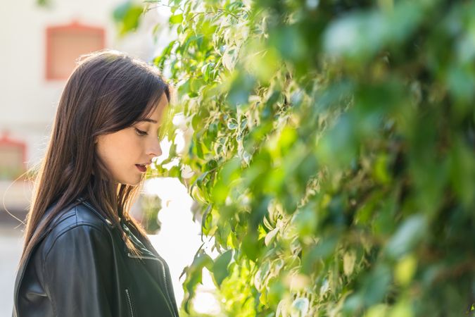Charming woman beside bush leaves on street