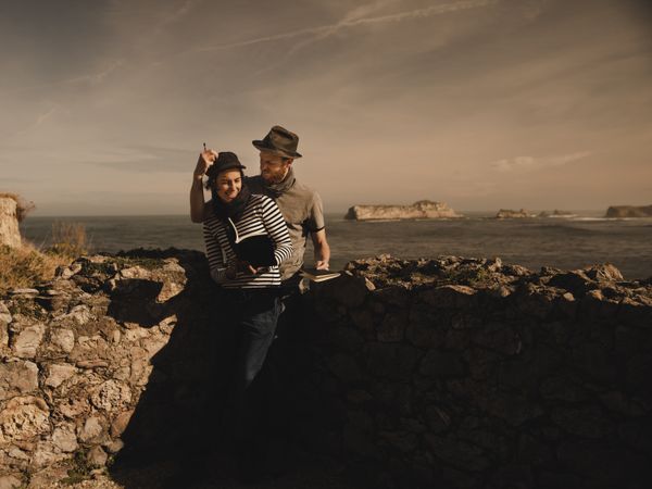 Man near woman with books near stones on shore