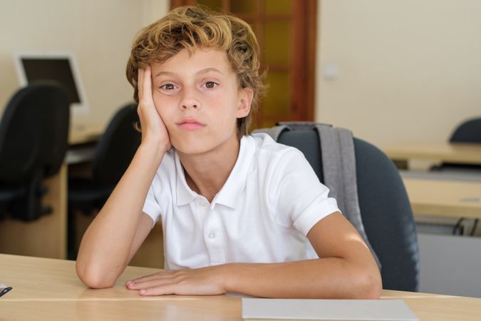 Frustrated schoolchild sitting at table in classroom