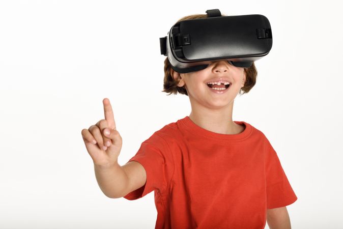 Smiling girl looking in VR glasses and gesturing with finger pointing up