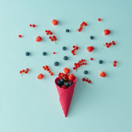 Red waffle cone with berries on blue background