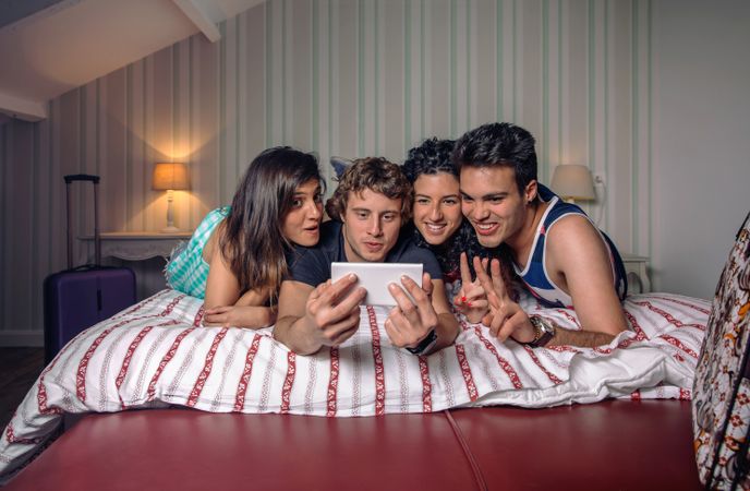 Friends lying on bed checking phone