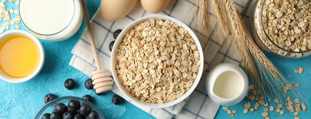 Composition with oatmeal flakes on blue background. Cooking breakfast
