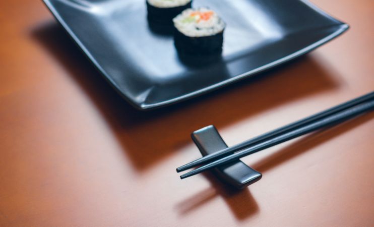 Chopsticks on restaurant table with sushi in background
