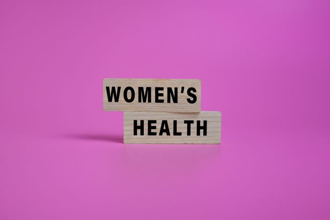 women health words text on wooden blocks isolated on pink background