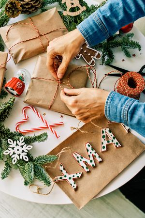 Anonymous person wrapping Christmas gifts on table