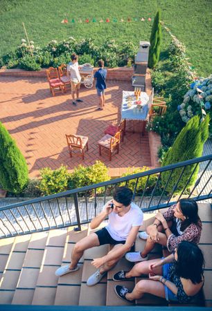 Looking down at man calling by phone sitting on home stairs