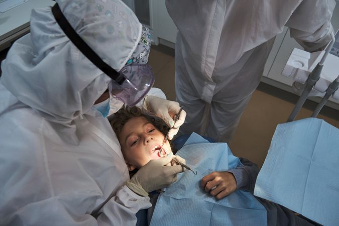 Dentists examining preteen patient in medical office