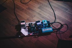 Pedal board for electric guitar in pink neon lighting on concert venue stage