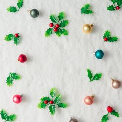 Pattern of plastic holly and baubles on snow background