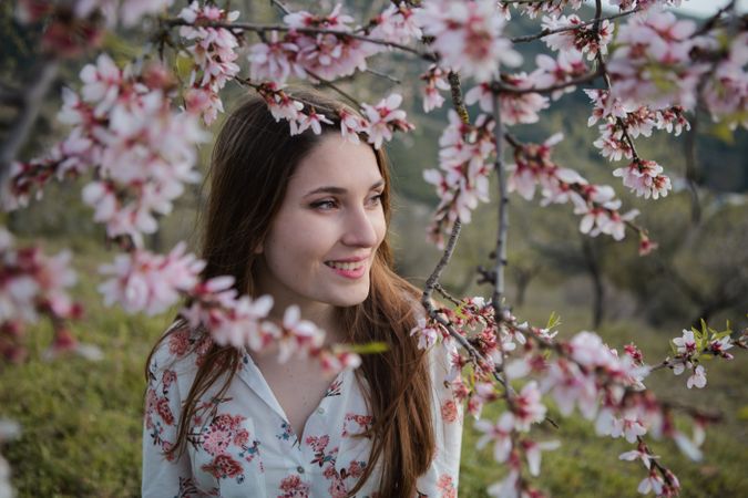 Young happy woman between trees in garden