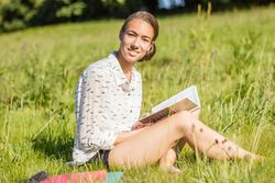 young student reading a book in the park
