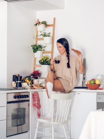 Cheerful female with coffee having breakfast at home