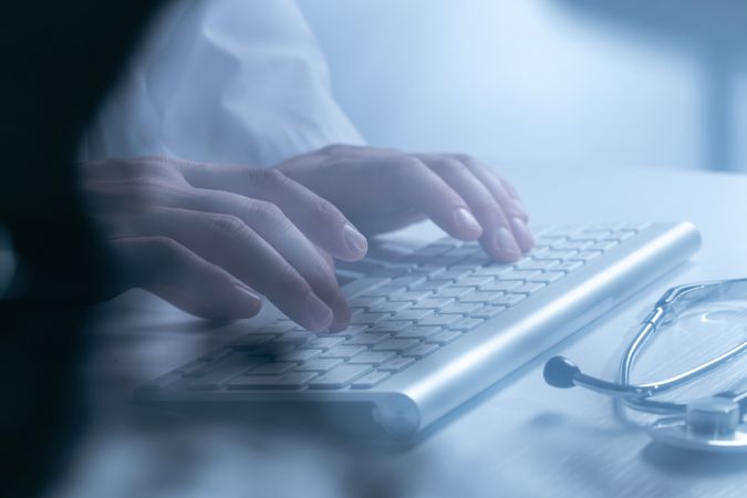 Doctor working at computer keyboard through X-ray film