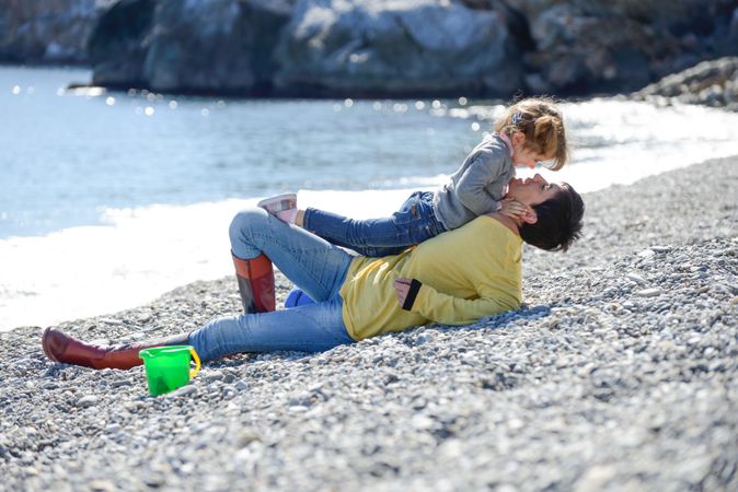 Girl climbing on her mother on the beach