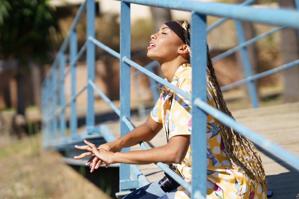 Female relaxing on pedestrian bridge enjoying the sunshine on her face