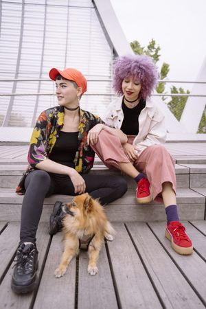 Women in colorful shirt and with pink hair training dog and having fun