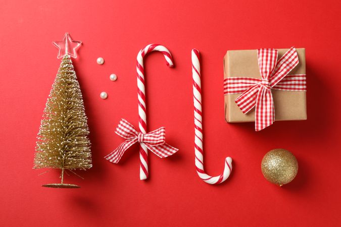 Candy canes and christmas accessories on red background, space for text