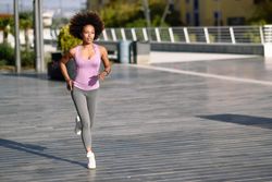 Woman with afro hairstyle running outside on pavement