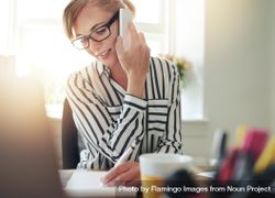 Woman in striped shirt taking phone call at her desk 5nG9n4