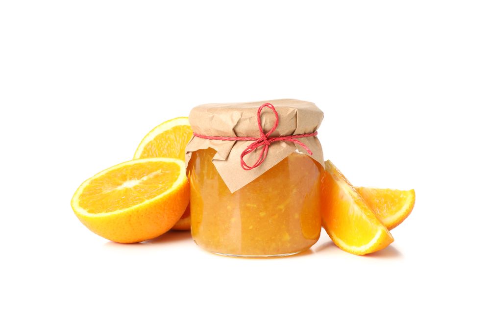 Glass jar with orange jam and ingredients isolated on blank background