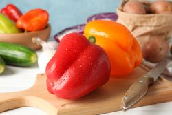 Vegetables, board and knife on wooden background, close up