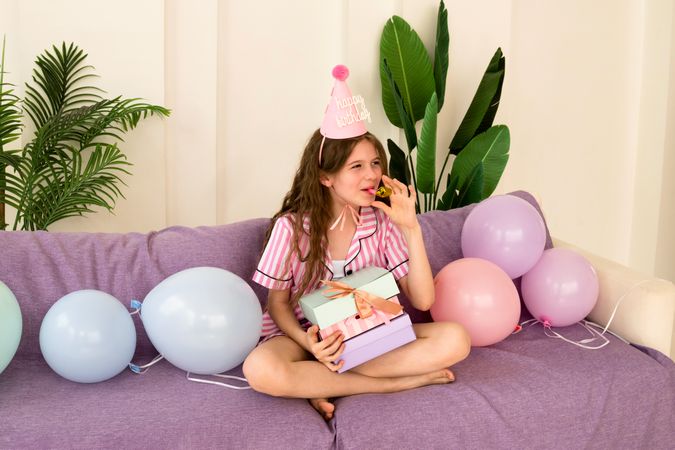 Young girl celebrating her birthday at home, holding presents.