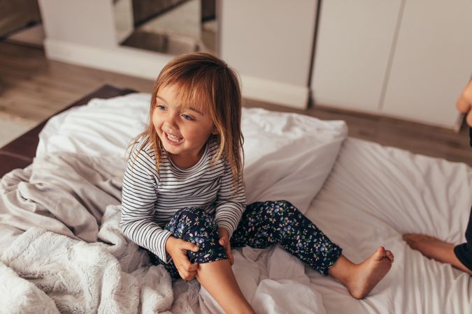 Happy girl playing on bed at home