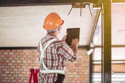 Back view of an engineer in bump cap using tablet computer