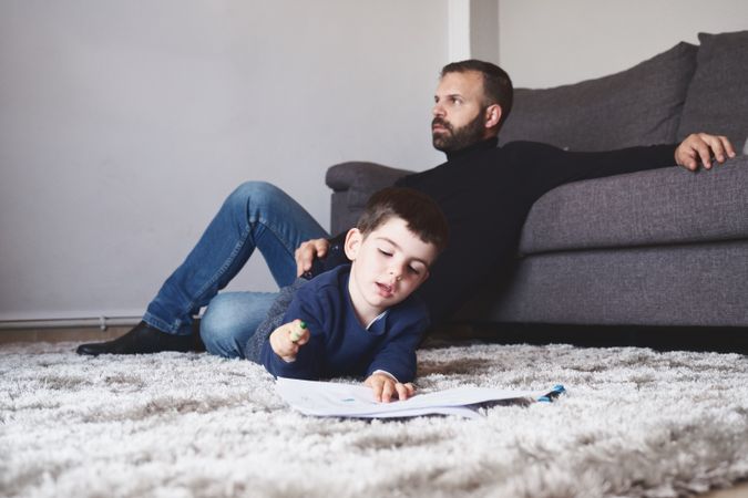 Son drawing on floor next to his father