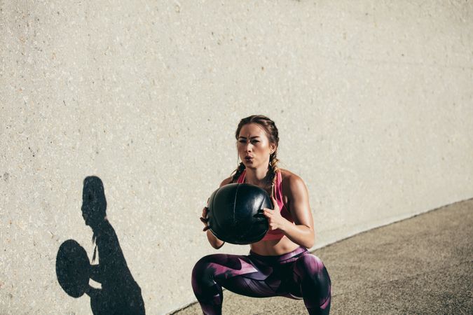 Sportswoman doing squat exercises with fitness ball