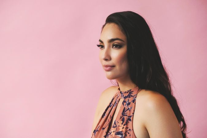 Side view of serious Hispanic woman in pink room