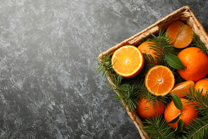 Basket with mandarins and pine branches on gray smoky background