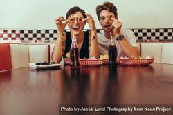 Smiling man and woman at a diner sitting with food and soft drinks on the table 5aq1o5