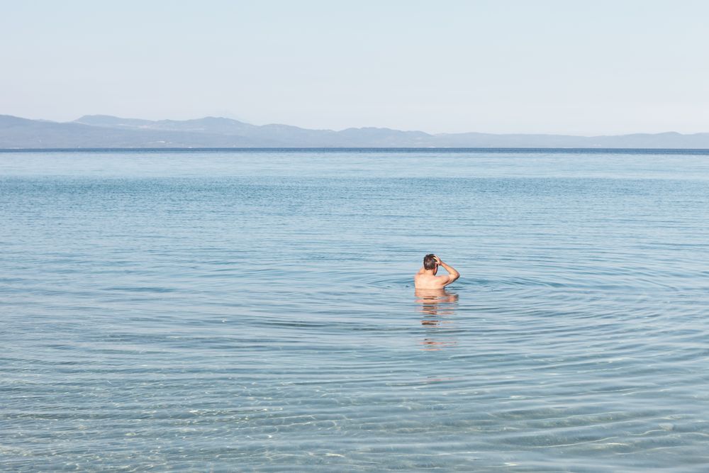 Man swimming in clear water in sunlight
