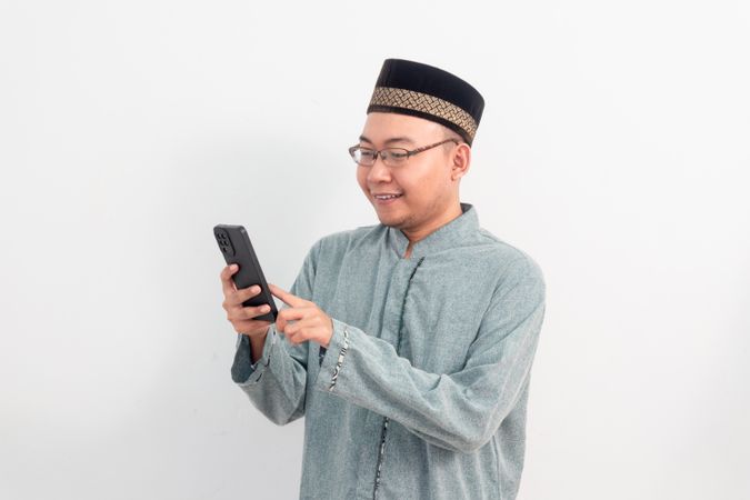 Asian Muslim man smiling holding phone pose, Ramadan