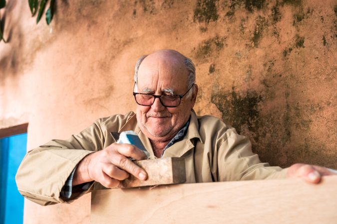 Mature man shaping wood with plane tool