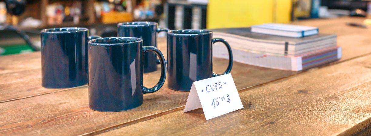 Banner of breakfast blue mugs over wooden counter in local store with industrial style decoration
