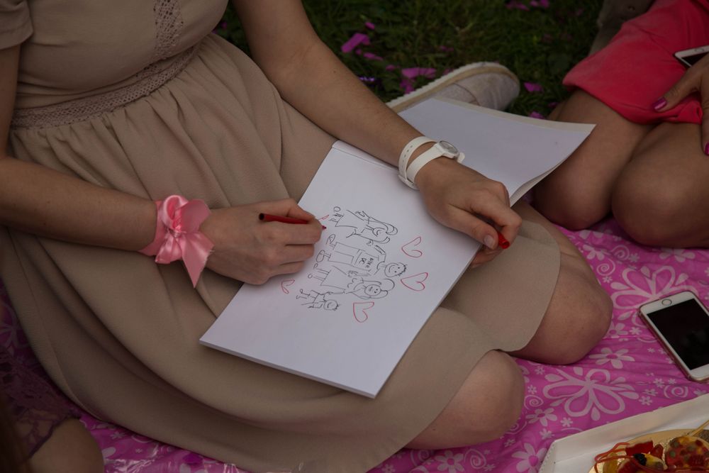 Cropped image of woman drawing a family on paper