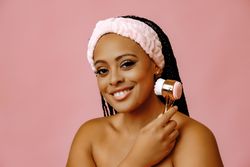 Content woman with her hair back in spa headband using facial brush