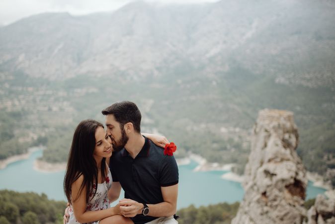 Affectionate casual couple embracing and resting on mountain top