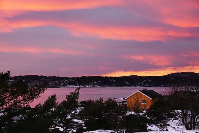 Colourful sunset over lonely house on frozen riverside