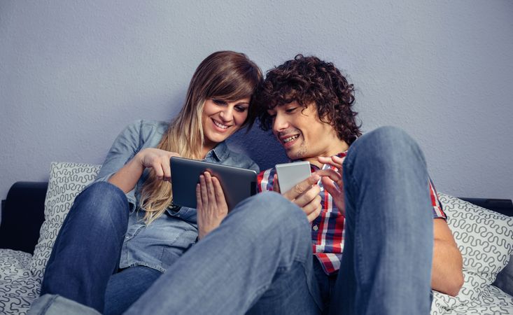 Couple in love looking electronic tablet and laughing relaxing in bed