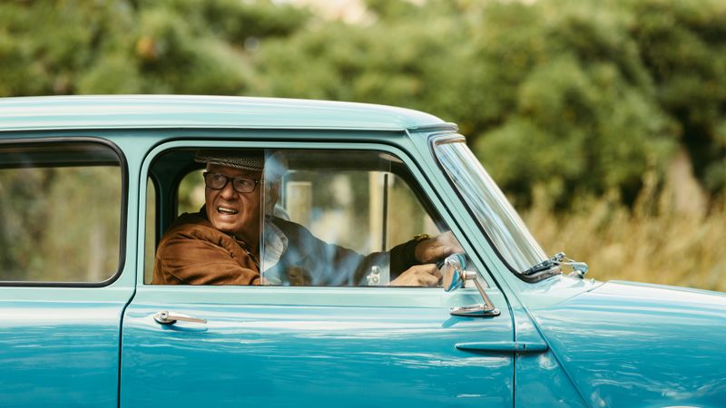 Mature man looks out of the window of his car before making a turn on road
