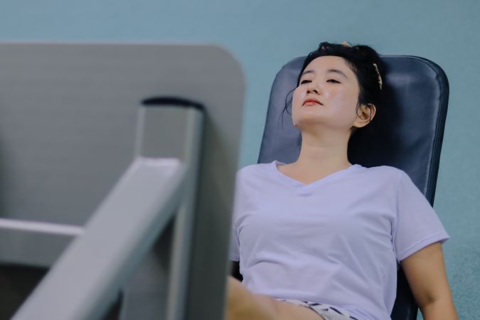 A young woman sits on a leg press machine