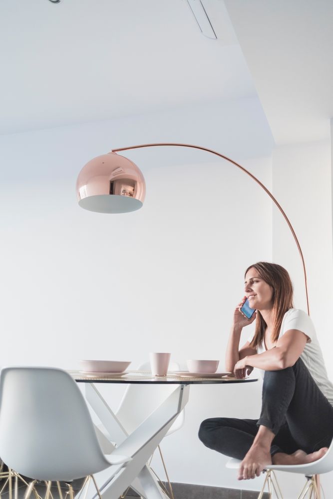 Woman sitting at sunny breakfast table talking on phone in front of cereal bowl